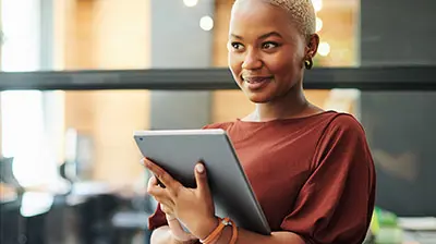 A woman holding a tablet in her hands while looking off to the side 